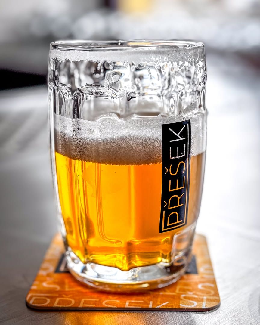 Točené světlé pivo s hustou pěnou ve sklenici na pivním tácku